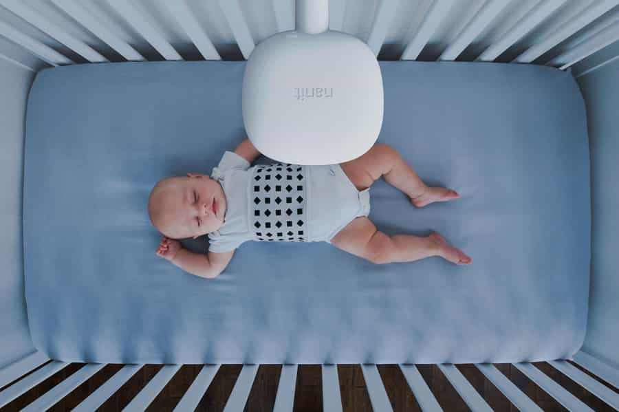 Image of babies in crib. Above the babies head is a Nanit camera